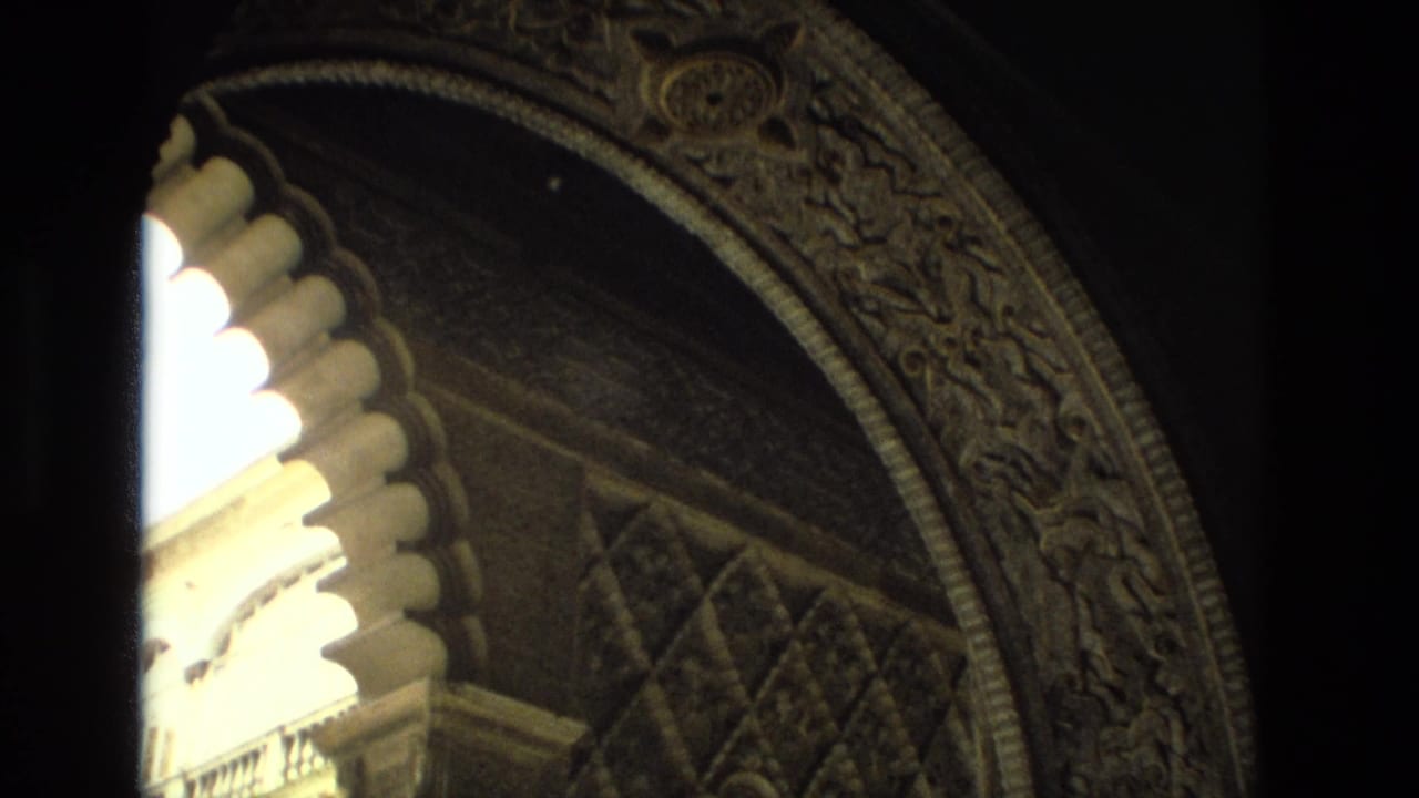 Close view of ornate scalloped arches and carved patterned stonework in a shadowed historic interior.