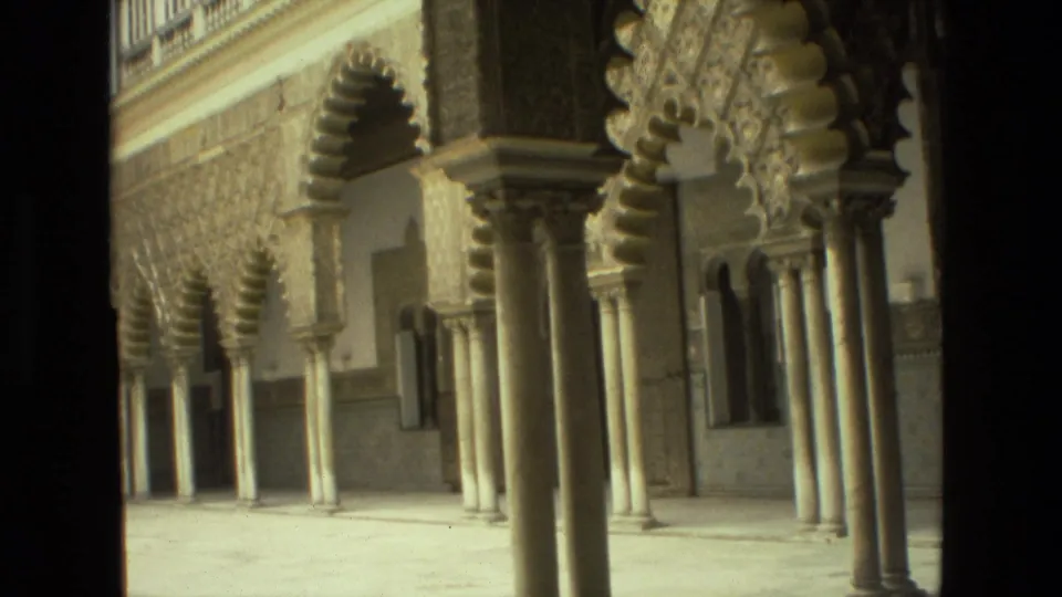 Seville 1978 home-movie frame of repeating arches, columns, and textured wall decoration in warm, faded 8mm color.