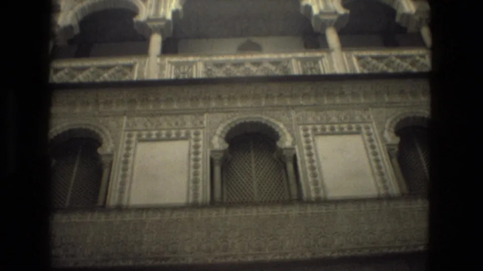1978 Seville architectural detail showing upper-level arched openings, lattice screens, carved bands, and worn 8mm frame edges.
