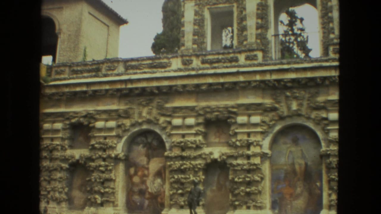 Ornate stone facade with arched painted niches and upper openings in bright daylight.