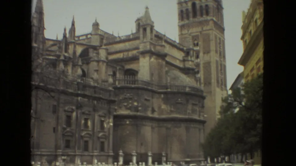 1978 8mm view of Seville Cathedral in Spain, showing Gothic stonework and the Giralda tower under a pale sky.