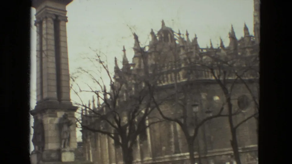 1978 Seville view showing a tall stone monument near the cathedral, with Gothic roofline details and winter-looking trees.