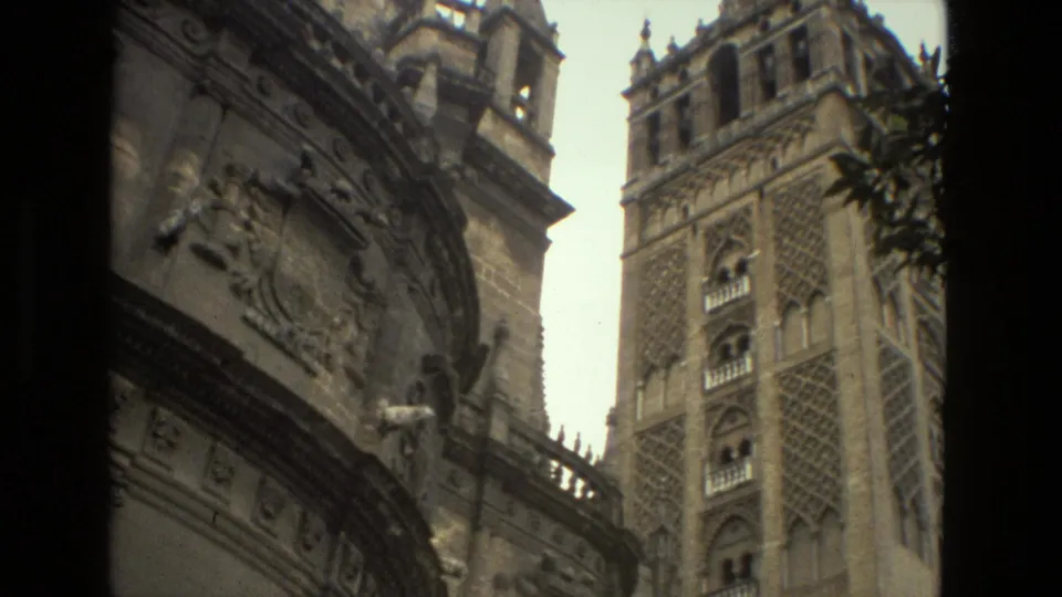1978 Seville frame with ornate stone architecture in the foreground and the Giralda tower rising at right.