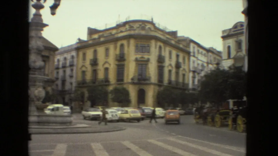 A 1978 Seville square view shows vintage cars, pedestrians, a stone fountain, a horse-drawn carriage, and ornate corner buildings.