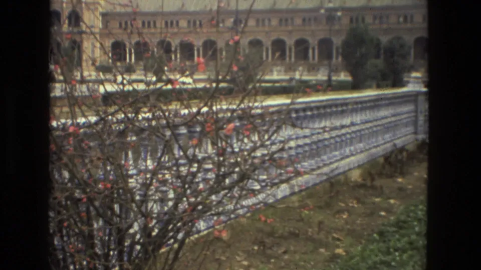 1978 Madrid exterior view showing flowering branches, a patterned railing, and a long arched colonnade behind it.