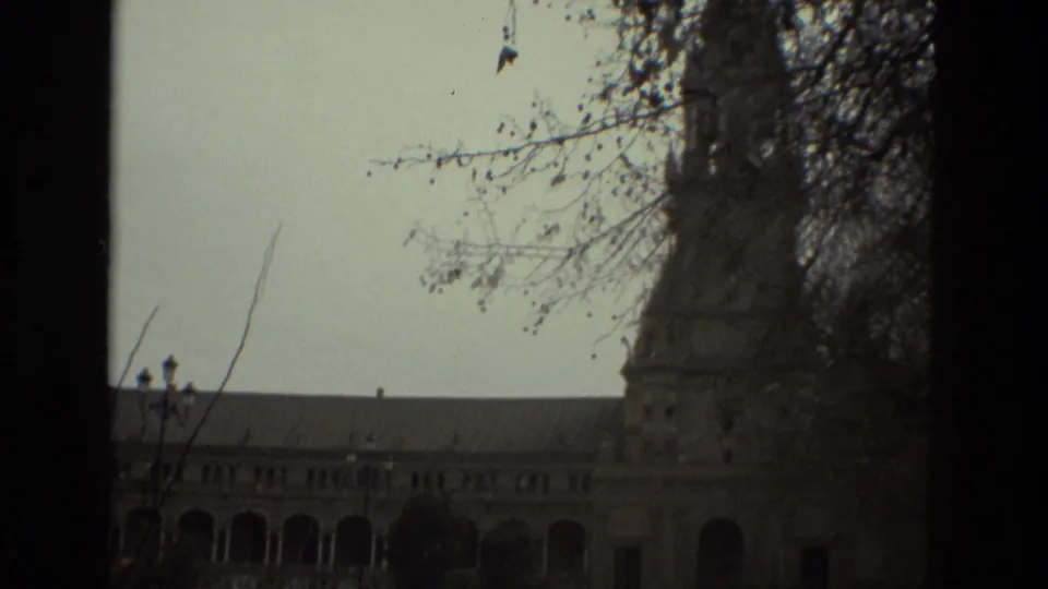 1978 Madrid exterior frame with a tower edge, roofline, tree branches, and a darker underexposed foreground.