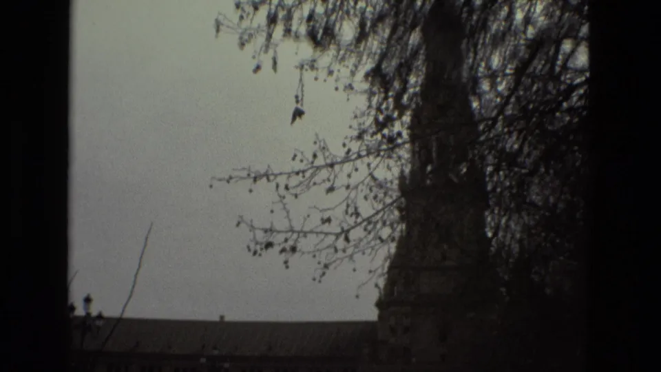 1978 Madrid 8mm frame showing a palace tower and long roofline partly obscured by bare branches and dark film edges.