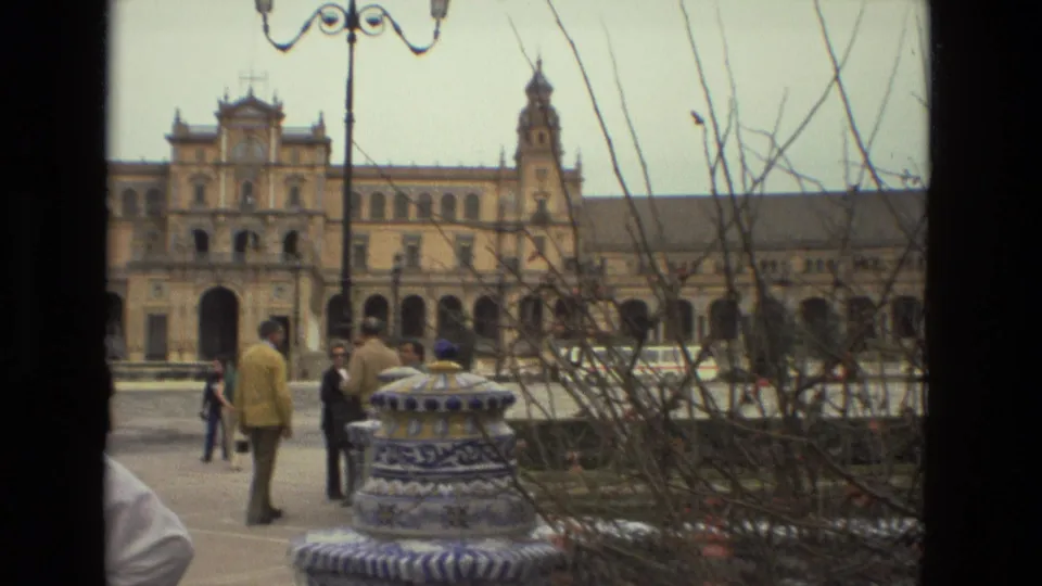 1978 home-movie view of pedestrians crossing near a tiled fountain at Plaza de España in Seville.