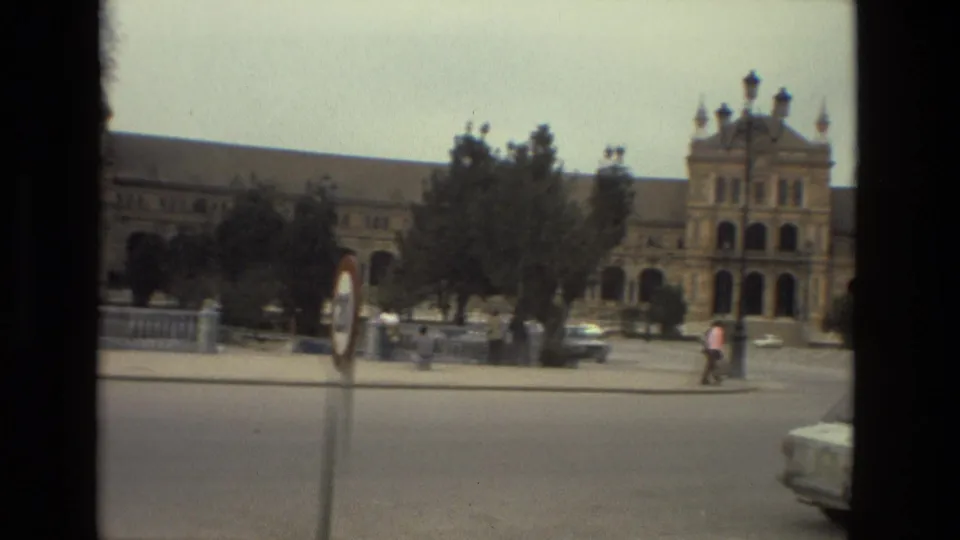 1978 Madrid frame of an ornate facade and arched entries seen beyond a broad road, with pedestrians and cars in the foreground.