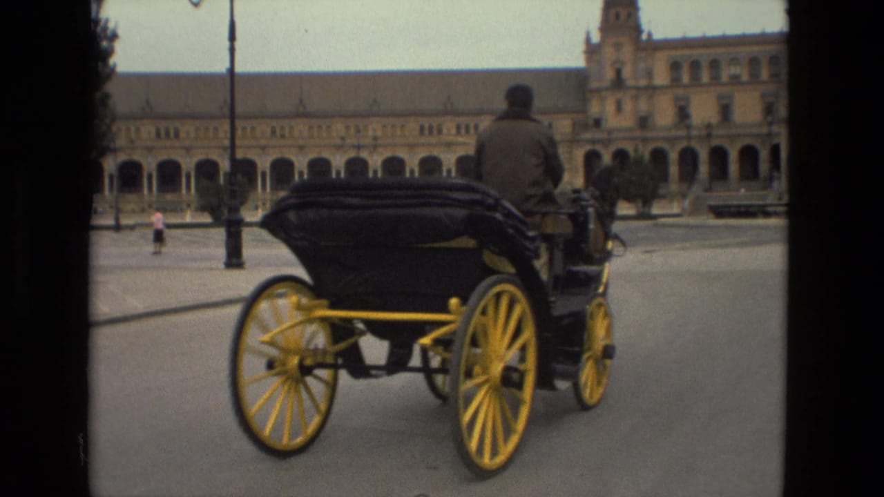 Horse-drawn carriage with yellow wheels crossing a large plaza.
