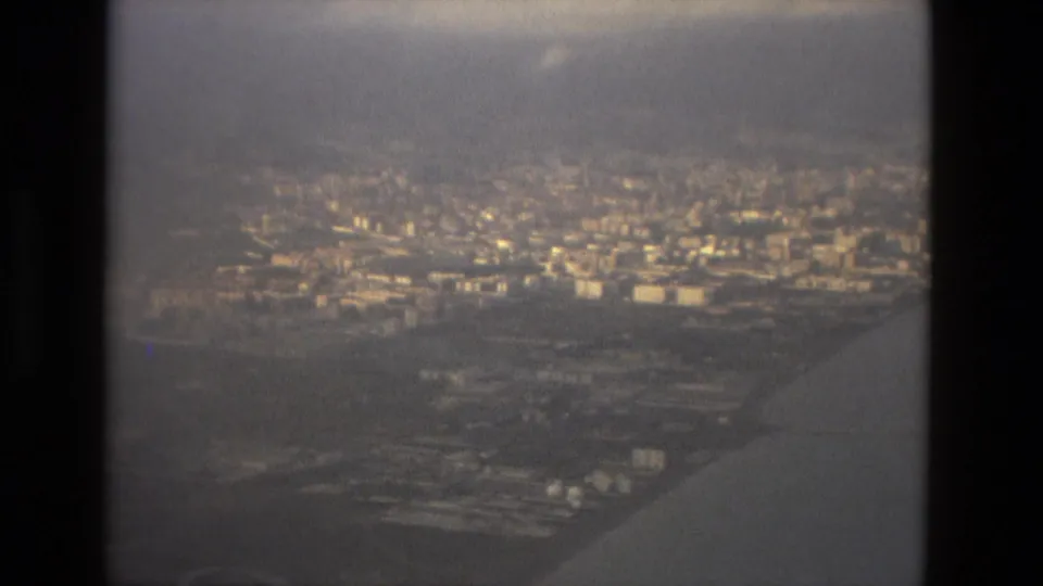 1978 Barcelona landing approach with the plane wing in the foreground and a dense cityscape under hazy light.