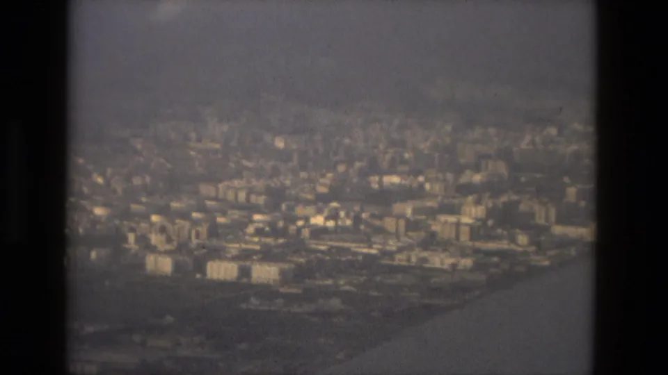 1978 Barcelona aerial approach showing denser buildings near the shoreline, filmed through a hazy aircraft window.