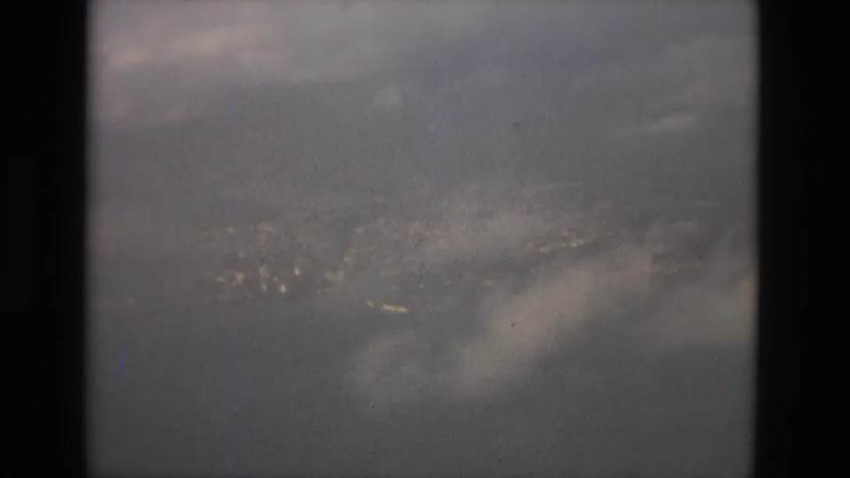 The final 8mm frame shows a hazy Barcelona coastline and water through the passenger-window framing.