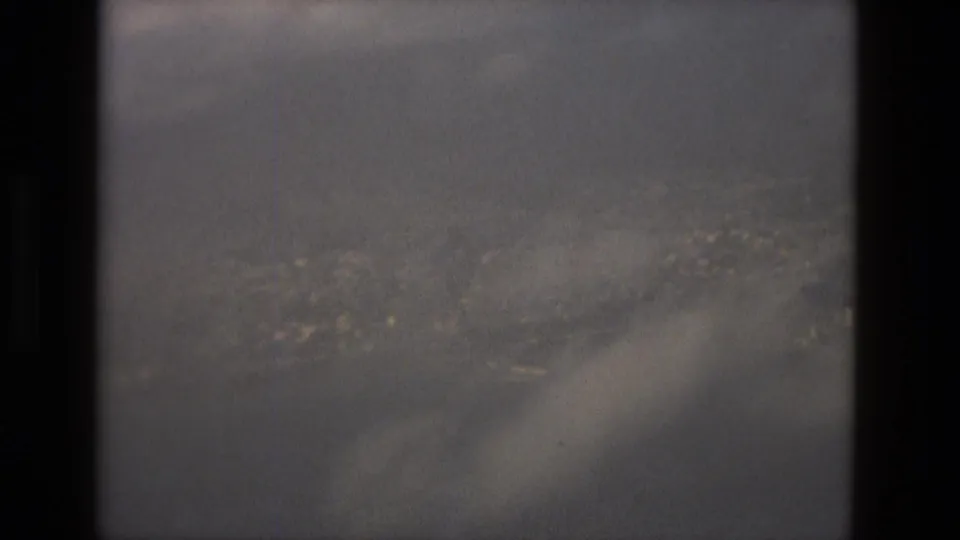 1978 Barcelona 8mm frame showing clouds over a distant urban view, partly obscured by dark scan borders.