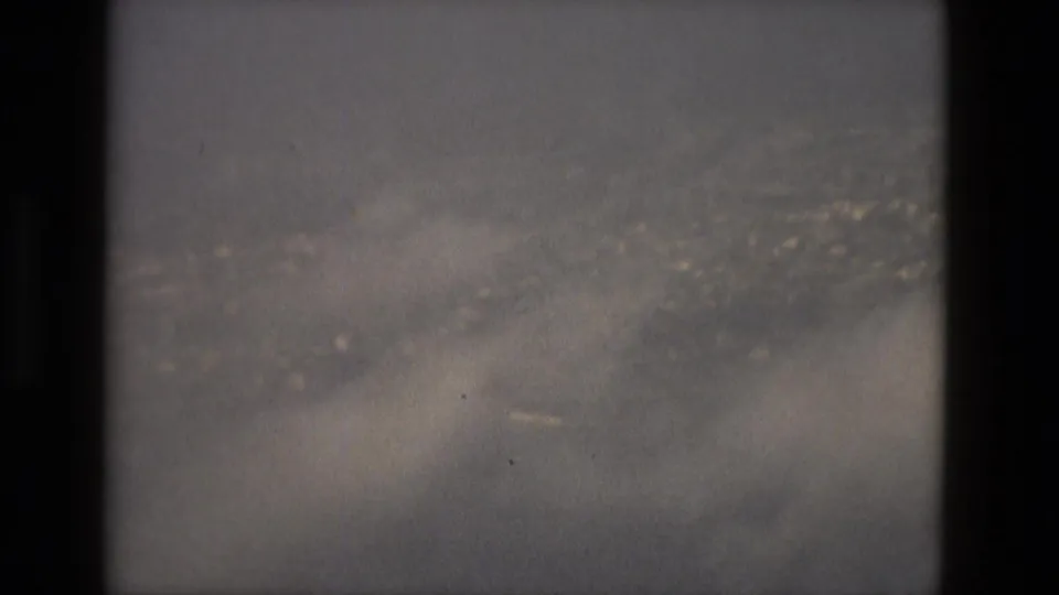 1978 Barcelona 8mm view of cloud cover and a soft distant cityscape, with the scan gate visible at the sides.
