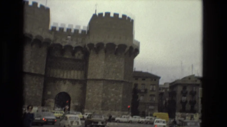 1978 Barcelona street frame showing the stone gateway with cars and pedestrians moving through the foreground.