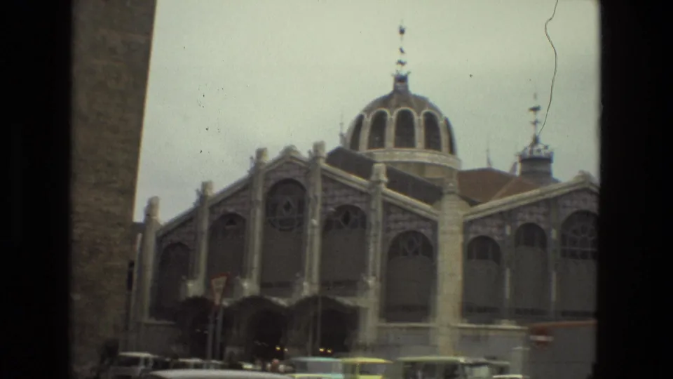 Barcelona 1978 8mm frame showing a domed building with tall arched windows above a street lined with cars.