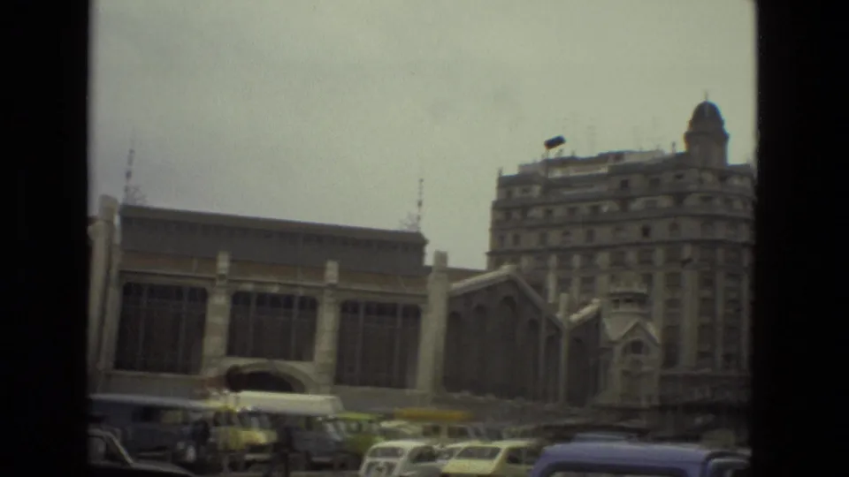 1978 Barcelona frame showing the building frontage, nearby multi-story architecture, and period cars gathered along the curb.
