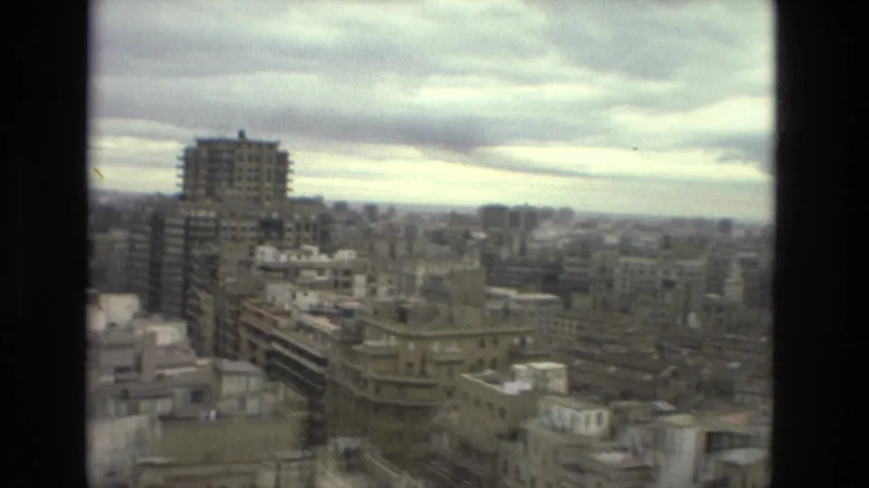 A 1978 Barcelona city view from a high balcony shows apartment blocks, rooftops, and a broad cloudy sky.