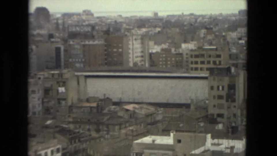 1978 Barcelona cityscape with rooftops, mid-rise buildings, a long pale wall, and dark window framing under overcast light.