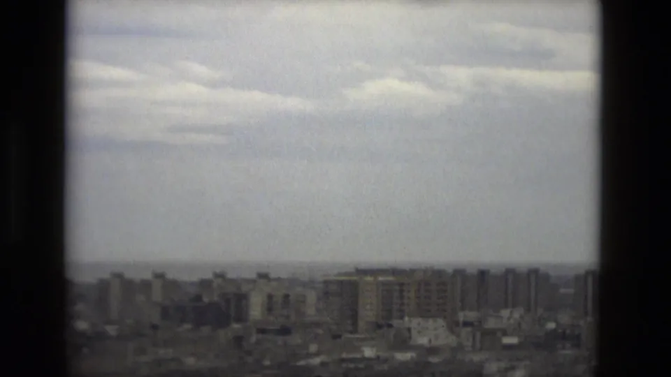 Barcelona skyline from a high vantage point, with distant mid-rise buildings and bright overcast sky.