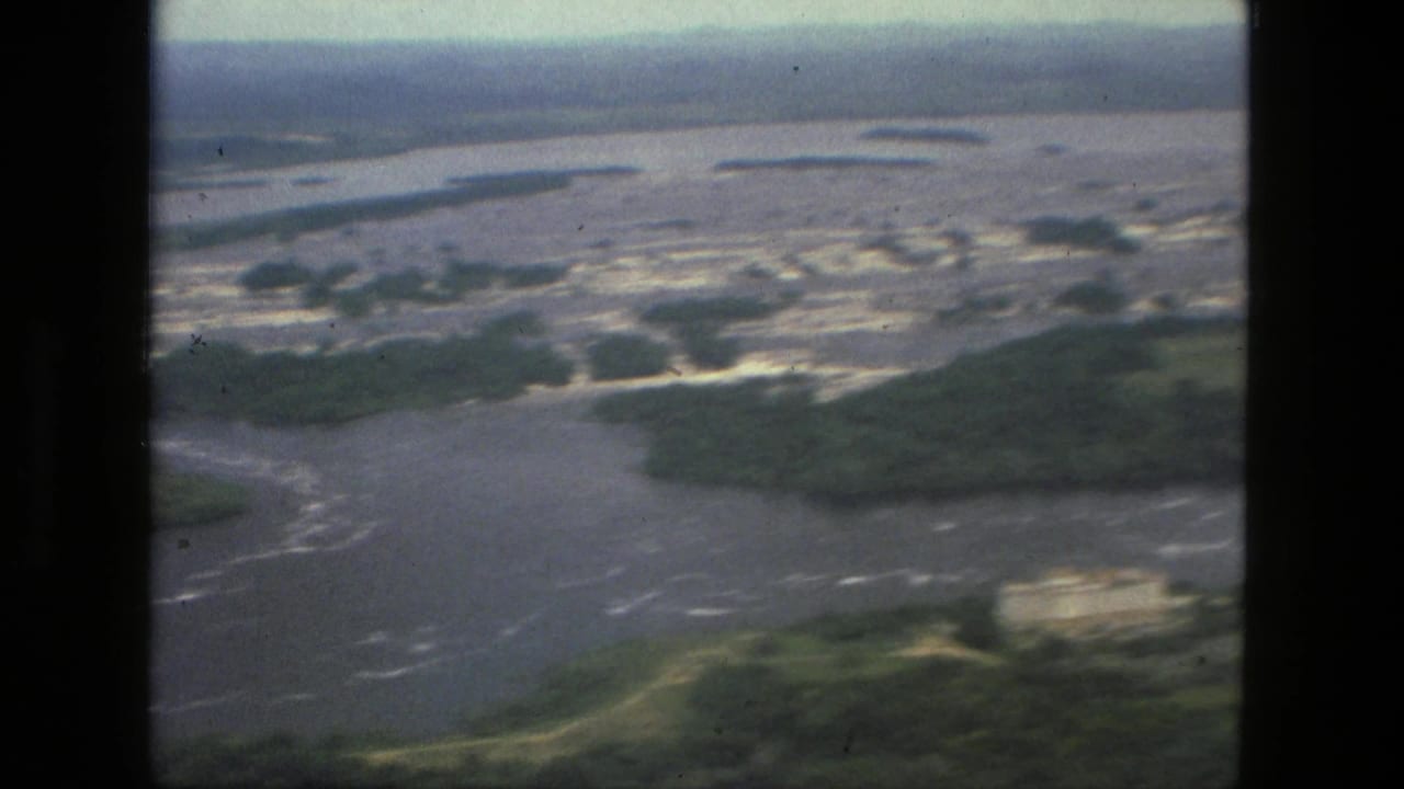 Aerial view of a broad river channel with green islands and shallow braided water.