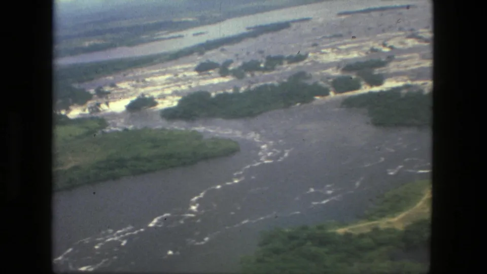 1979 Manaus-area aerial film frame with winding river water, green vegetation, and bright broken water near the channel edge.
