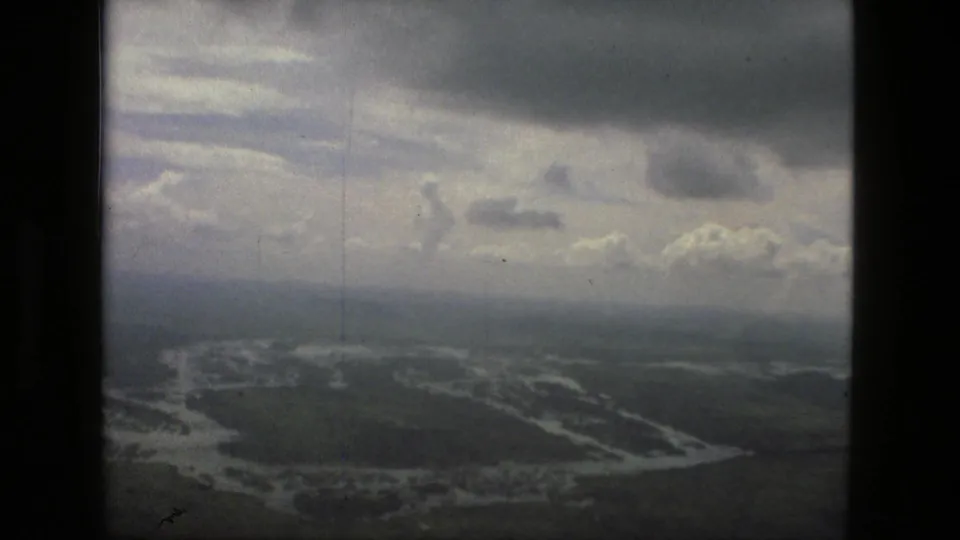 1979 Manaus 8mm aerial frame showing a cloudy sky over flooded channels and dark tropical landscape.