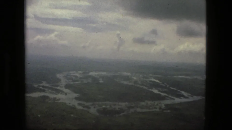 1979 Manaus aerial 8mm frame with gray cloud cover above flooded waterways and green tropical land.