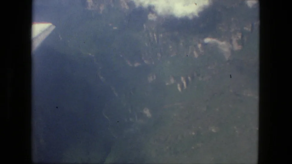 1979 8mm aerial frame near Manaus, Brazil, with a partial aircraft wing, window edge, water, and soft forested terrain below.