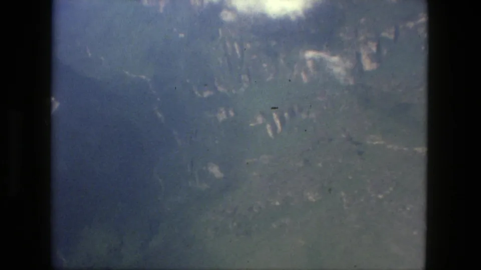 1979 Manaus, Brazil aerial 8mm frame showing hazy green mountain slopes and valley terrain below.