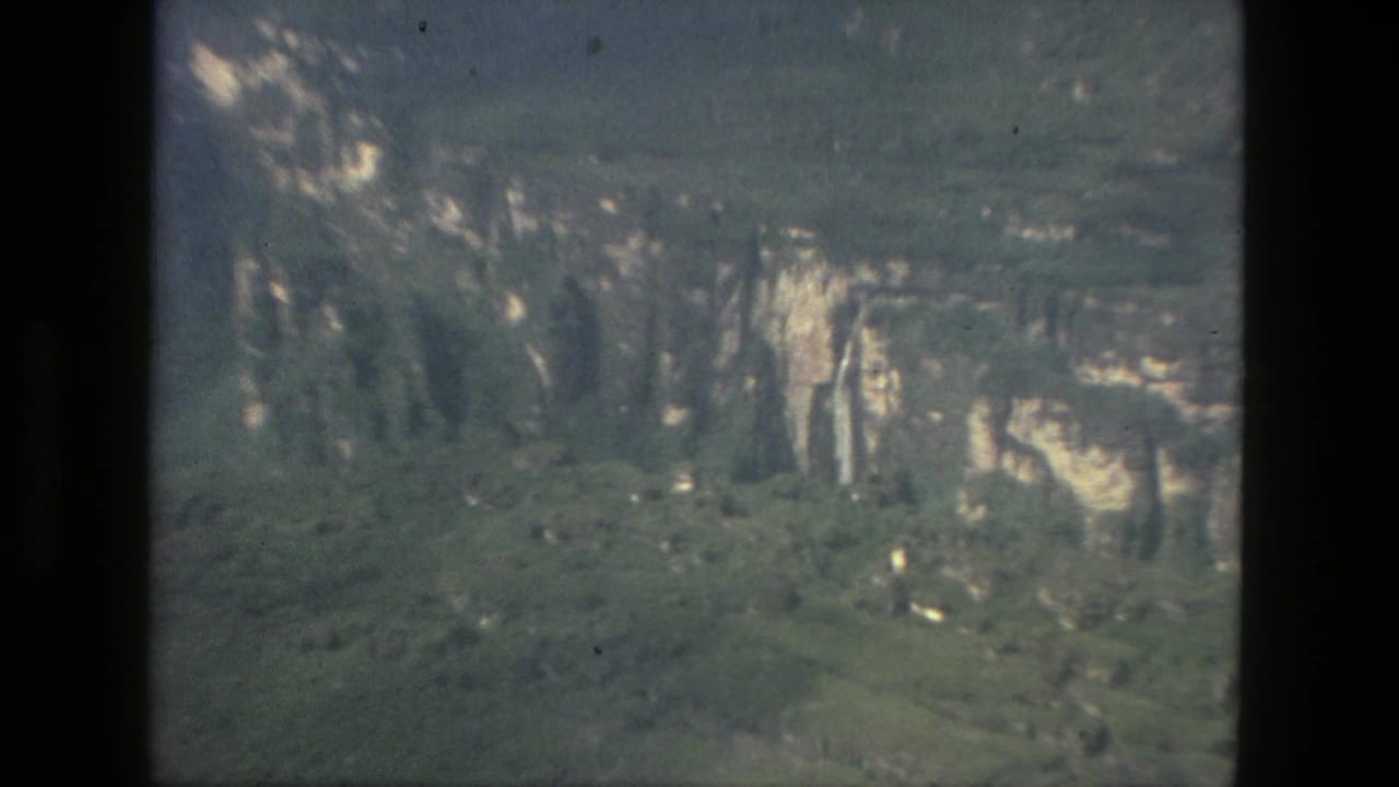1979 8mm home-movie frame from Manaus metadata showing a distant green landscape with pale rock faces and soft exposure.