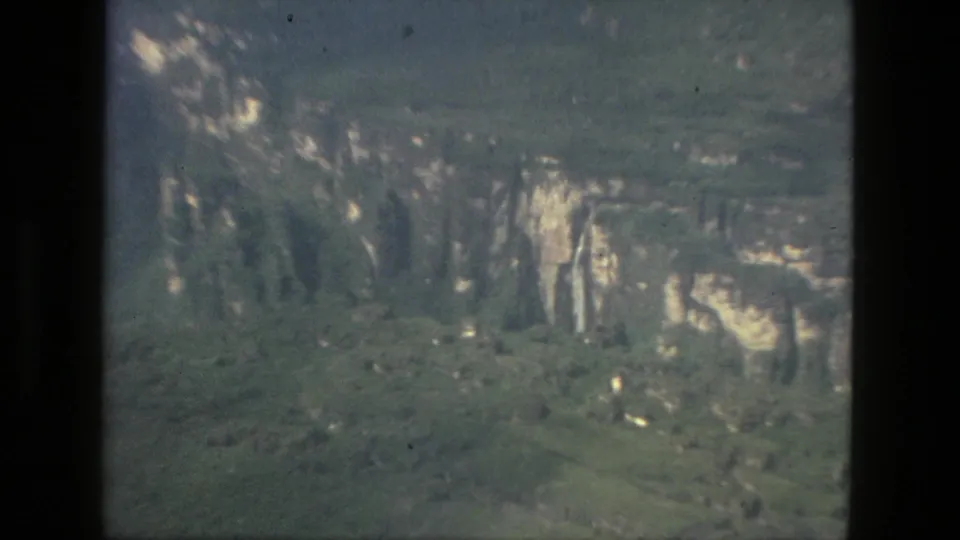 1979 8mm home-movie frame from Manaus metadata showing a distant green landscape with pale rock faces and soft exposure.