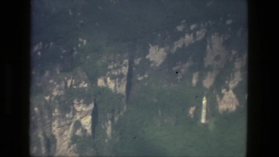 Aerial 8mm frame of wooded cliff walls near the stated Manaus, Brazil location, with faded color, soft detail, and rocky outcrops.