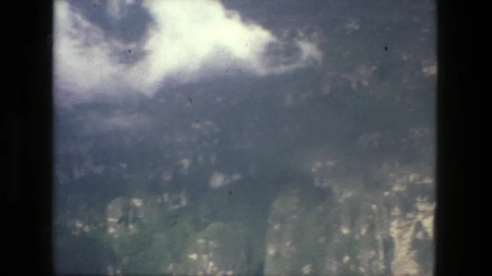Soft 1979 aerial home-movie frame near Manaus, Brazil, with green landscape below and bright cloud or haze across the upper left.