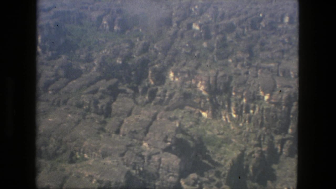Aerial view over forested rocky terrain with dark film gate edges.