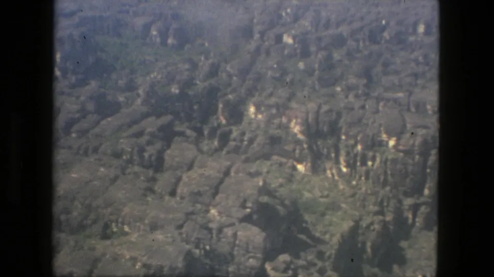 1979 8mm aerial footage near Manaus, Brazil, looking down over green vegetation and rugged rock formations.
