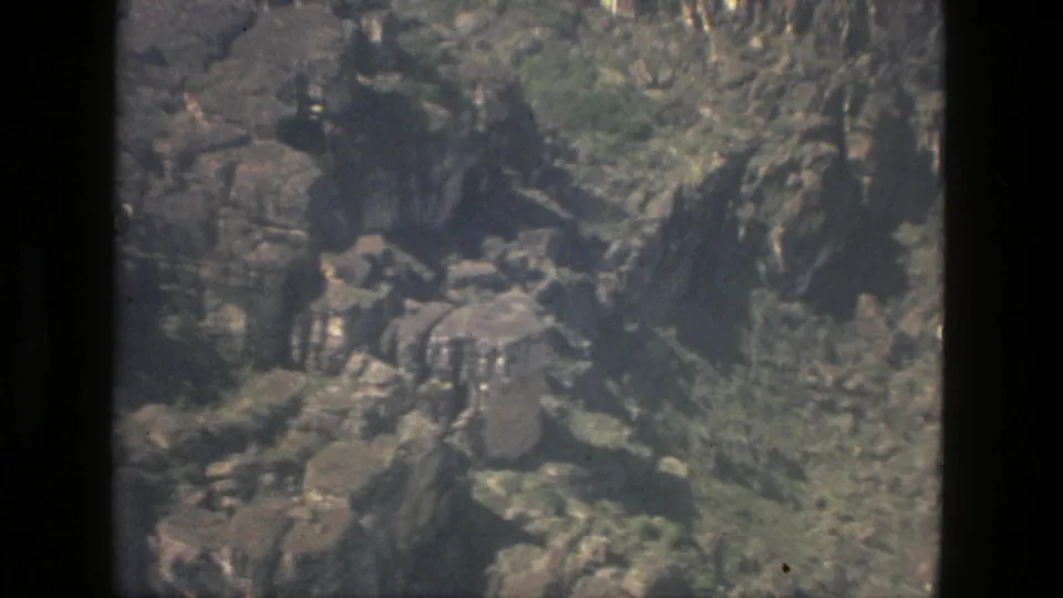 Aerial 8mm view near Manaus showing uneven rock faces, green tree cover, and shadowed cuts in the landscape.