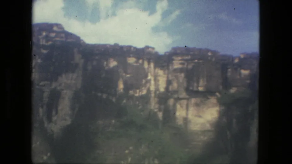 Soft 1979 8mm frame from the Manaus metadata showing distant cliffs, vegetation, and open sky.
