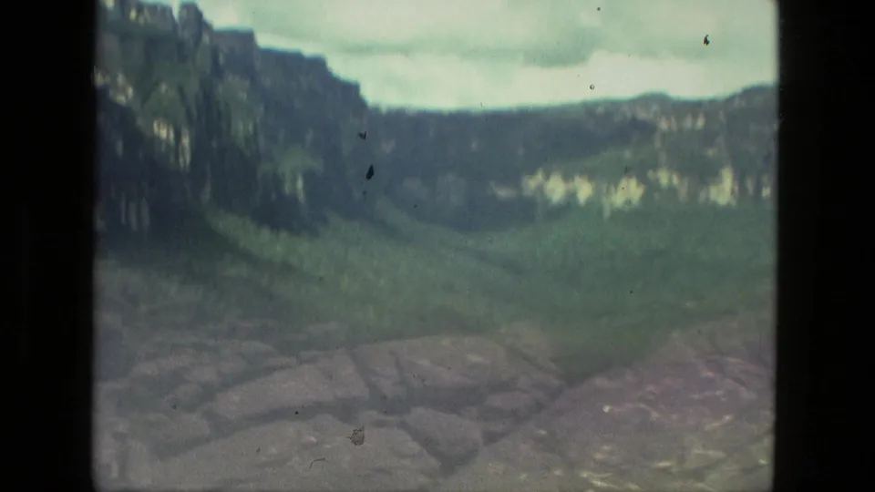 1979 8mm Manaus, Brazil footage looking across a misty green valley with rock formations in the foreground and an overcast sky.