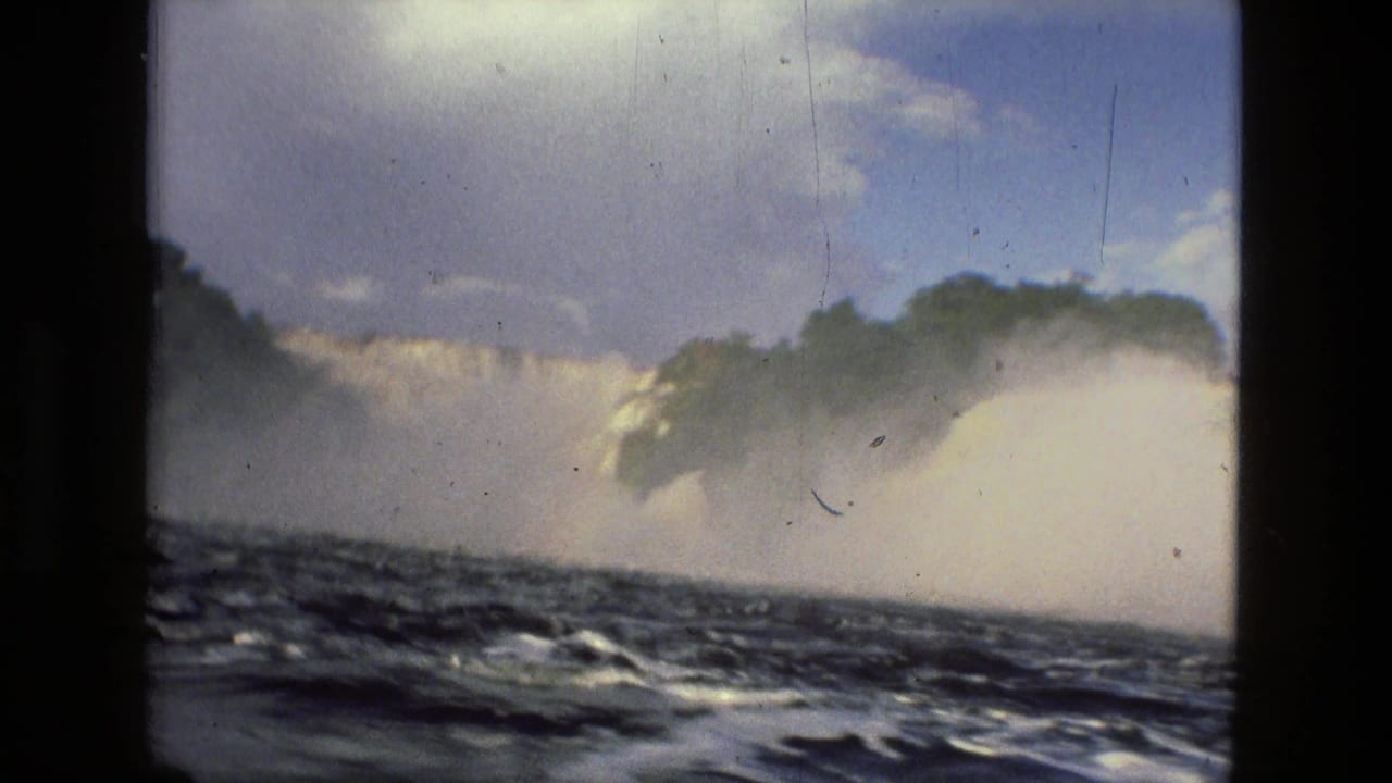 1979 8mm home-movie view near Manaus, Brazil, showing turbulent river water, mist, and a broad waterfall through dark film borders.
