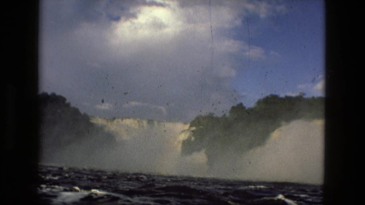 Waterfall, mist, trees, and rough river surface seen through a dark film frame.