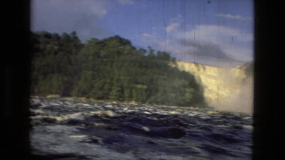 The 1979 Manaus, Brazil home-movie frame shows a wooded bank, choppy river foreground, and bright waterfall spray at the right side.