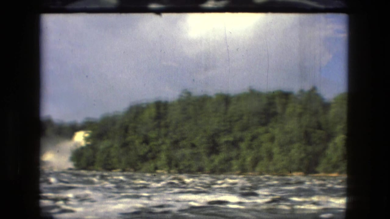 Forested riverbank and rough water visible beside a dark vertical window frame.