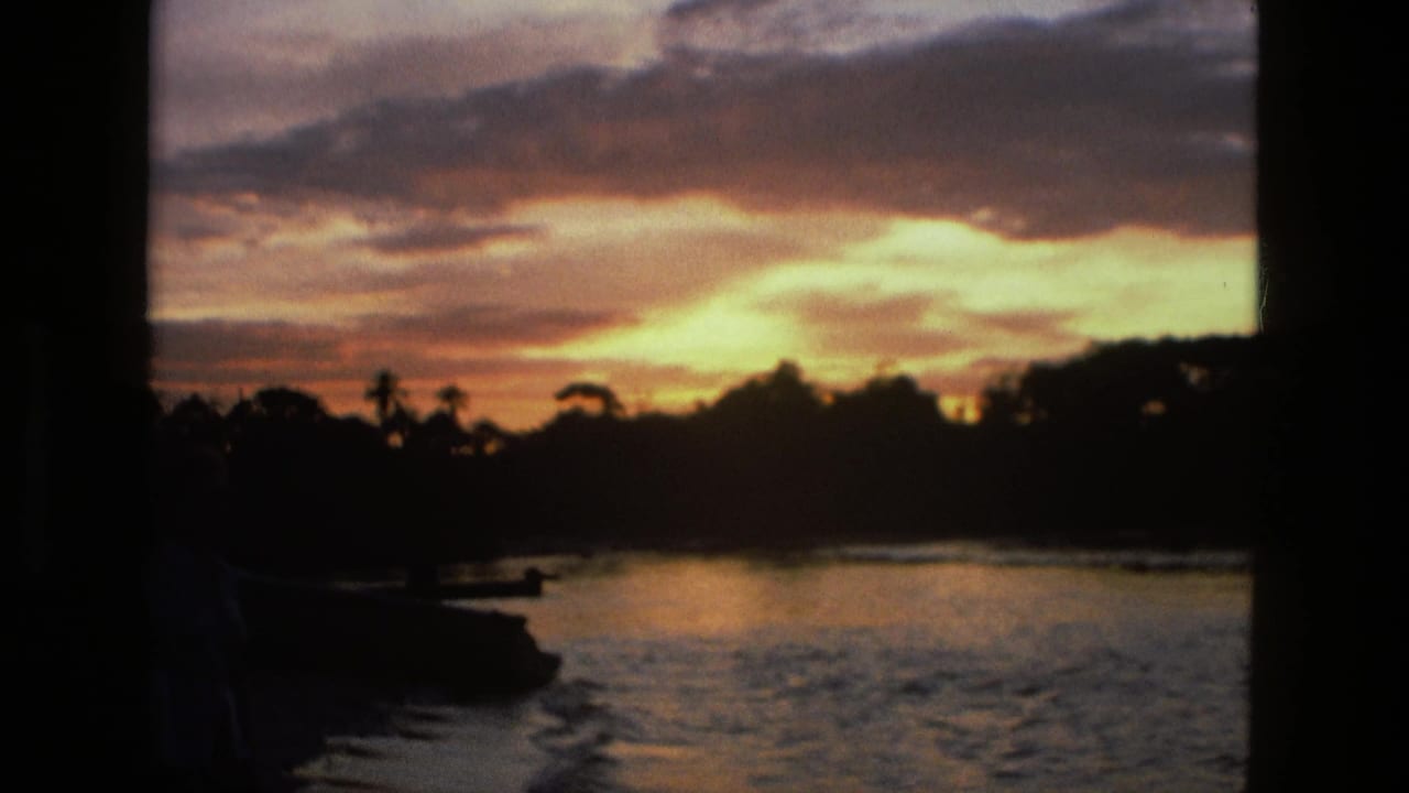 Dusk sky over water with a dark shoreline and small boat-like shape.