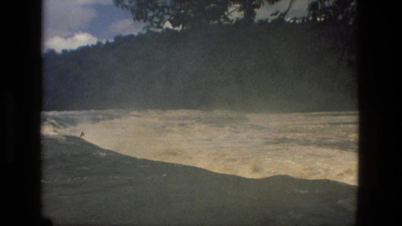 Churning rapids curve through a wooded landscape with hills and dark tree framing.