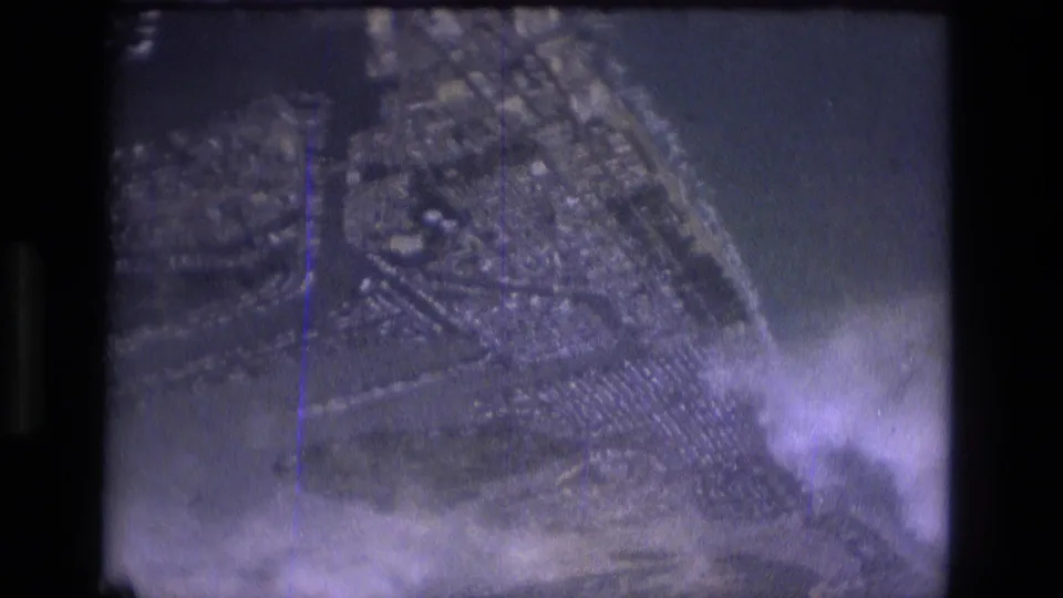 1979 Manaus aerial frame with roads and dense blocks visible through grain, haze, and purple-tinted 8mm exposure.