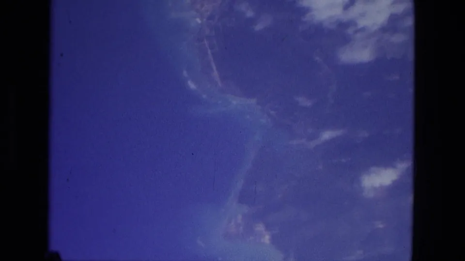1979 Manaus 8mm frame with blue sky, pale cloud streaks, and soft atmospheric haze inside a bordered film frame.