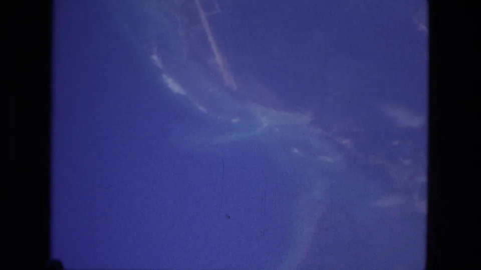 1979 Manaus 8mm frame showing blue sky, soft cloud patterns, and a dark contact-sheet divider across the scanned film image.