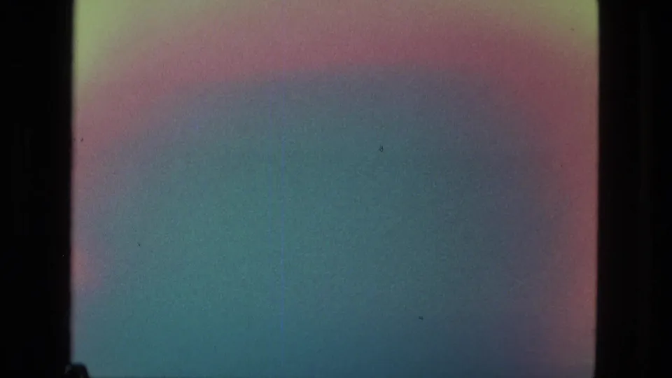 1979 Manaus 8mm frame with a rainbow-like flare, blue-green color wash, dark film border, and faint surface marks.